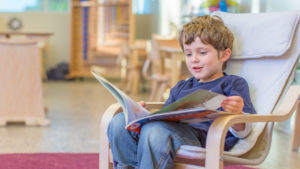 a boy in a chair holding a picture book